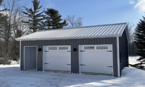 Two car garage with a white steel roof in Ontario surrounded by lush green lawn and trees on a sunny day